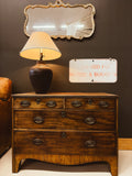 Georgian bow-front walnut chest of drawers — styled with lamp and mirror