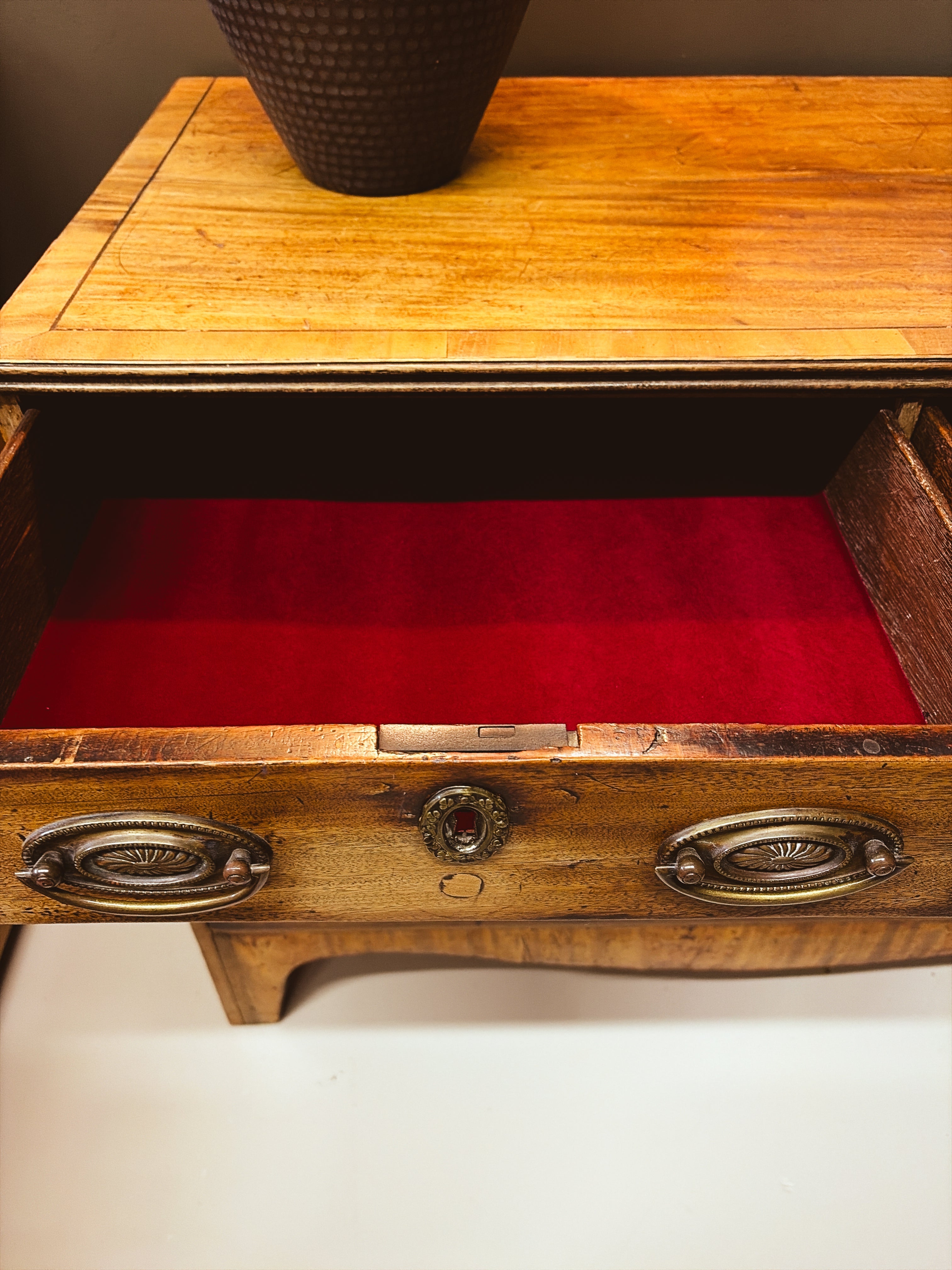Close-up of red velvet-lined drawer interior and oval brass hardware
