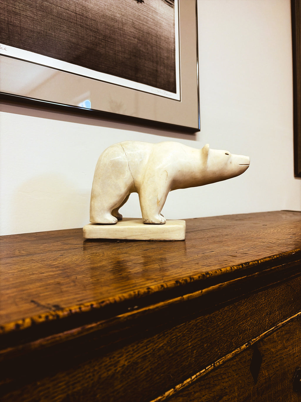 Inuit polar bear sculpture by David John Novoligak — side profile view on antique oak surface